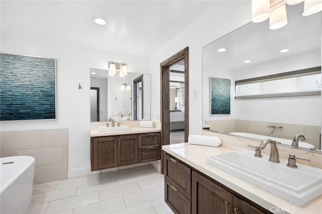 bathroom with a washtub, vanity, and tile patterned floors