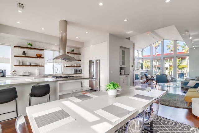 dining room featuring beamed ceiling, hardwood / wood-style flooring, high vaulted ceiling, and sink