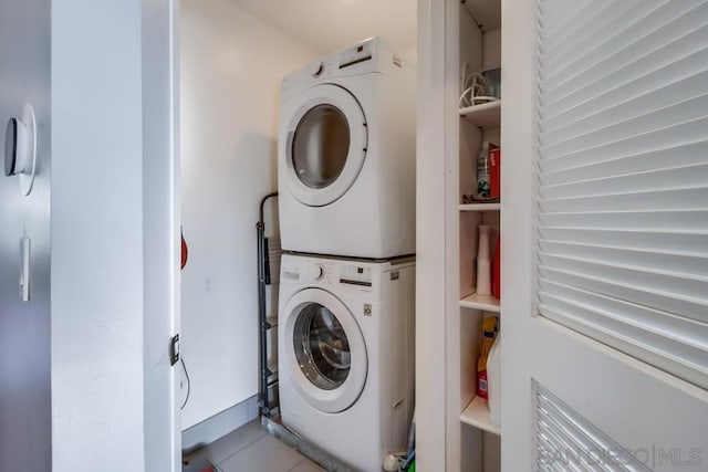 laundry area with tile patterned flooring and stacked washing maching and dryer