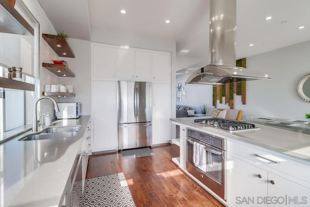 kitchen featuring sink, dark wood-type flooring, island range hood, white cabinets, and appliances with stainless steel finishes