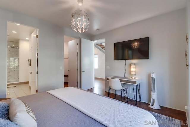 bedroom with ensuite bathroom, wood-type flooring, and an inviting chandelier