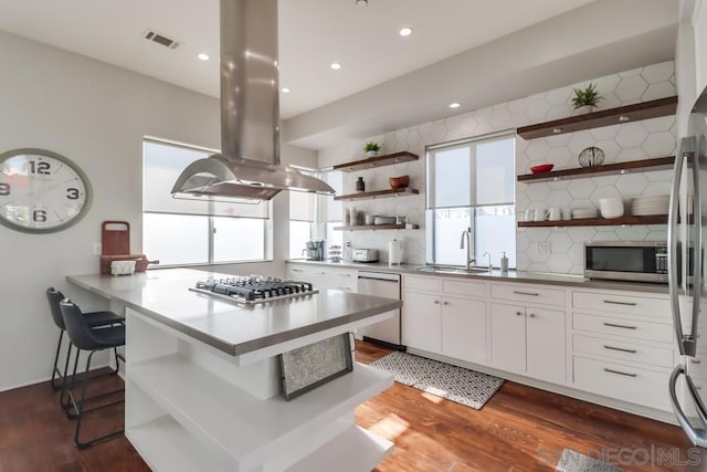 kitchen featuring island exhaust hood, tasteful backsplash, stainless steel appliances, sink, and white cabinetry