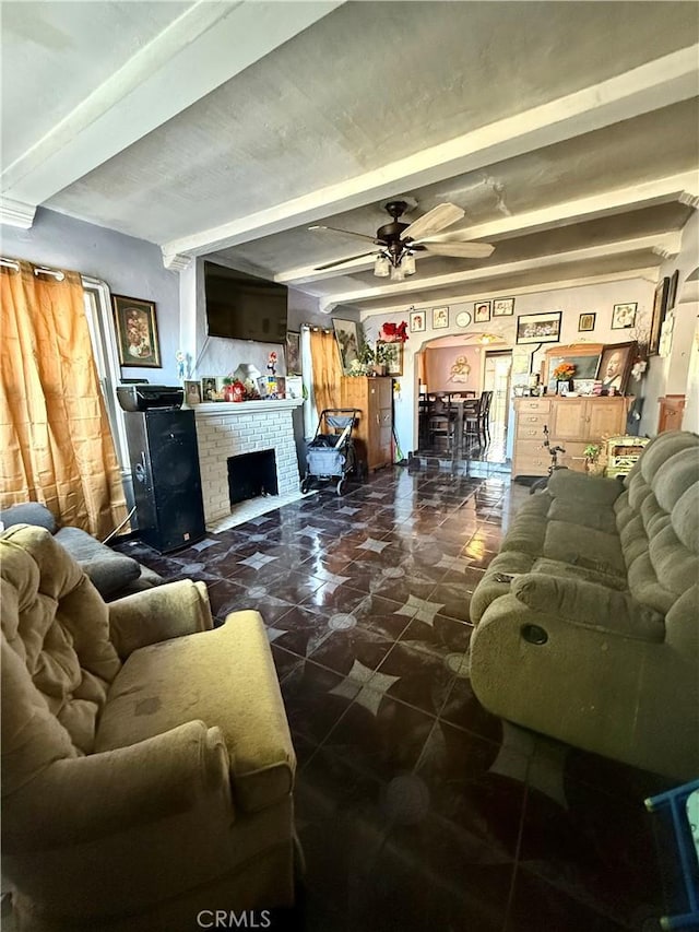 living room with beamed ceiling, ceiling fan, and a brick fireplace