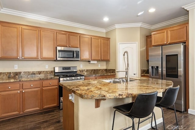 kitchen featuring an island with sink, sink, dark hardwood / wood-style flooring, a kitchen bar, and stainless steel appliances