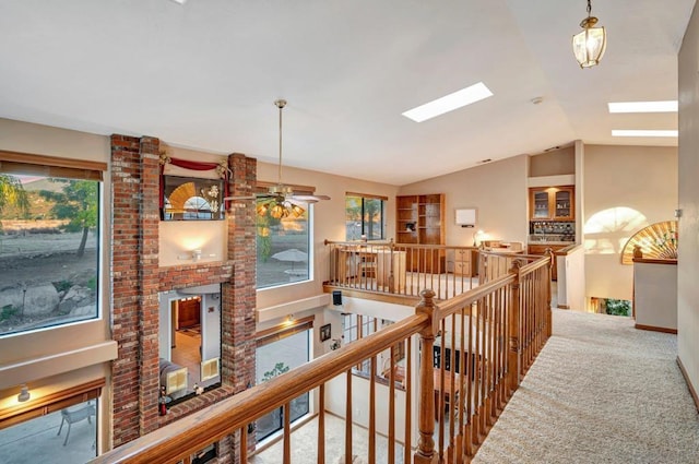 hallway with vaulted ceiling with skylight and carpet flooring