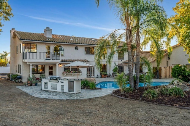 rear view of house with area for grilling, a balcony, and a patio