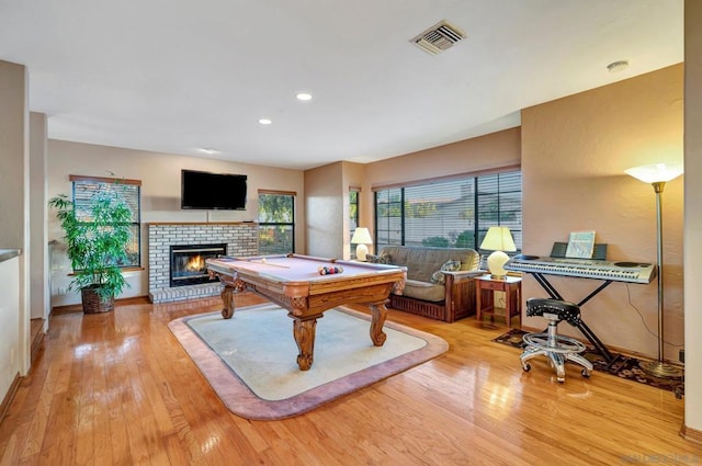 recreation room with billiards, light hardwood / wood-style floors, and a brick fireplace