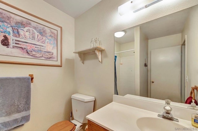 bathroom with a shower, vanity, and toilet