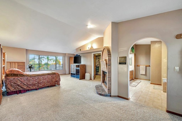 carpeted bedroom with a fireplace, connected bathroom, and lofted ceiling