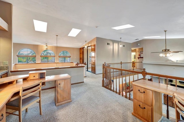 office featuring light colored carpet, ceiling fan, and vaulted ceiling with skylight