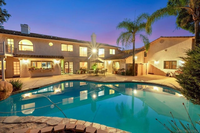 pool at dusk featuring a patio