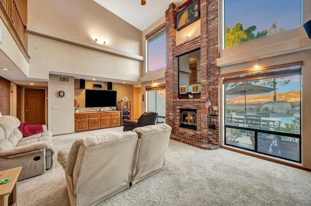 carpeted living room featuring a towering ceiling and a brick fireplace