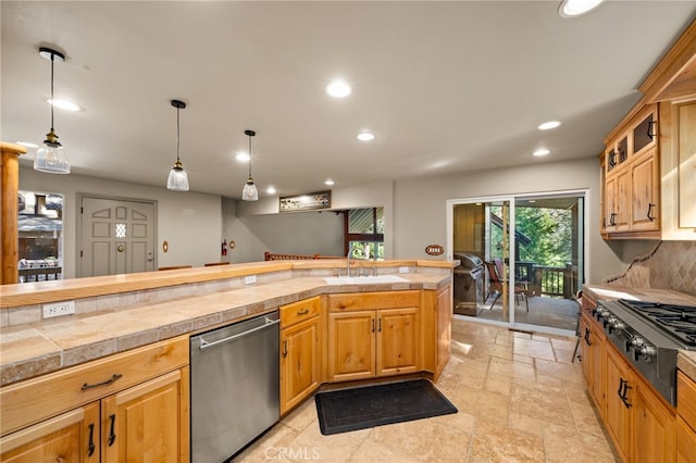 kitchen with appliances with stainless steel finishes, backsplash, decorative light fixtures, and sink