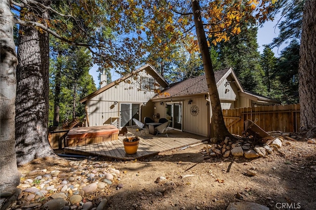 back of house with a covered hot tub and a deck