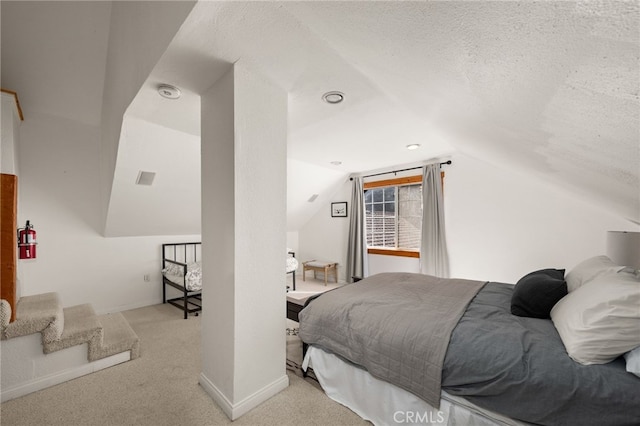 bedroom featuring a textured ceiling, light colored carpet, and lofted ceiling