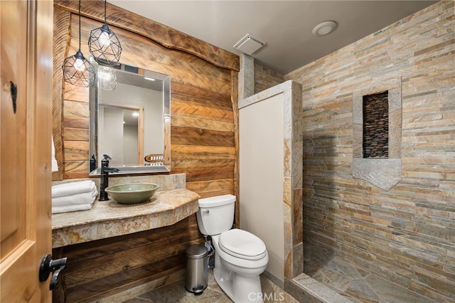 bathroom featuring vanity, toilet, walk in shower, and wood walls