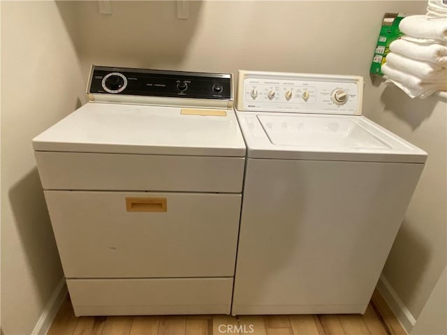 clothes washing area featuring separate washer and dryer and light hardwood / wood-style floors