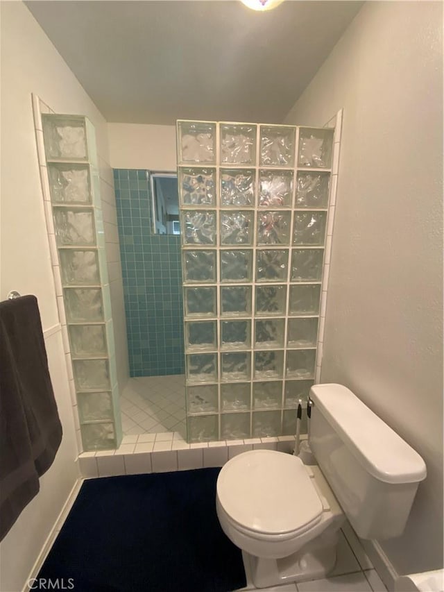 bathroom with tile patterned floors, toilet, and a tile shower