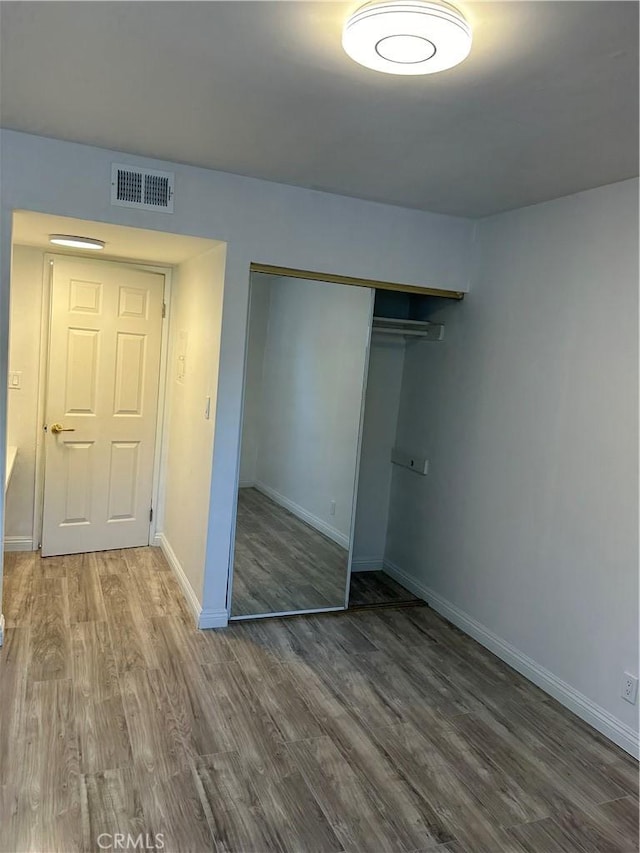 unfurnished bedroom featuring a closet and hardwood / wood-style flooring