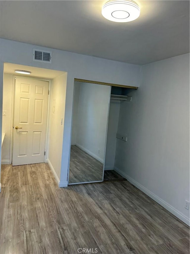 unfurnished bedroom with hardwood / wood-style flooring and a closet