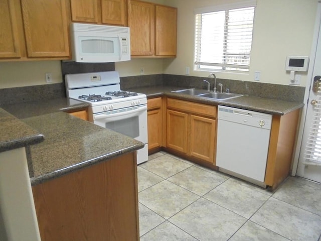 kitchen featuring light tile patterned flooring, white appliances, and sink