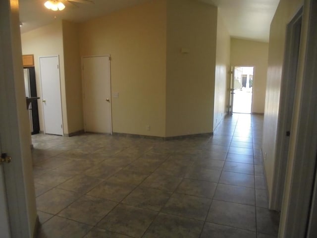 tiled empty room with ceiling fan and lofted ceiling