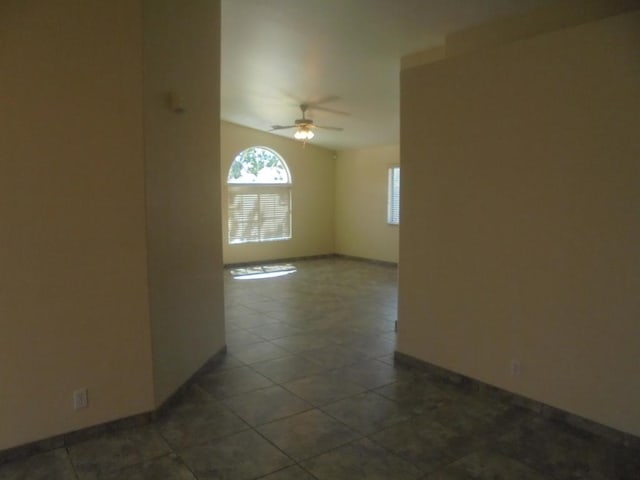 empty room featuring ceiling fan and dark tile patterned floors