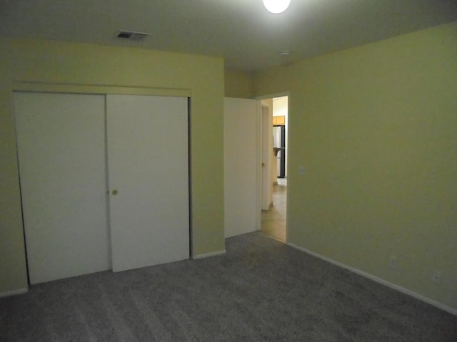 unfurnished bedroom featuring dark carpet and a closet