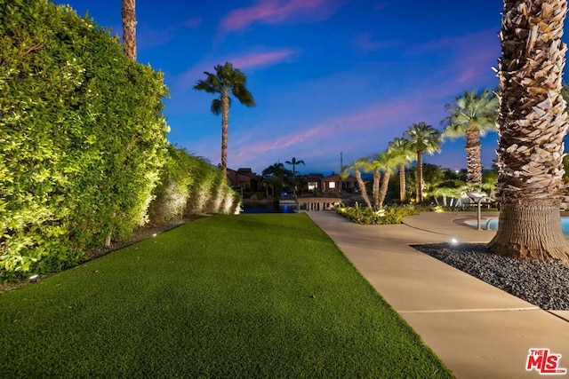 yard at dusk featuring a water view