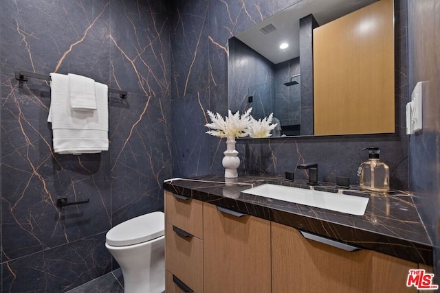 bathroom featuring vanity, tile walls, and toilet