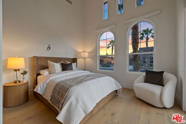 bedroom featuring light hardwood / wood-style floors and a high ceiling