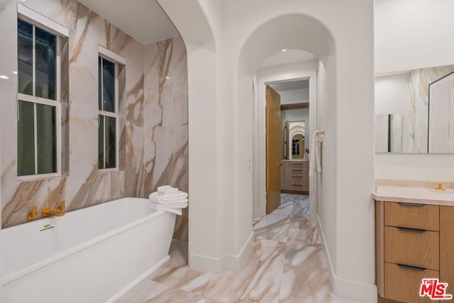 bathroom featuring a bathtub, tile walls, and vanity