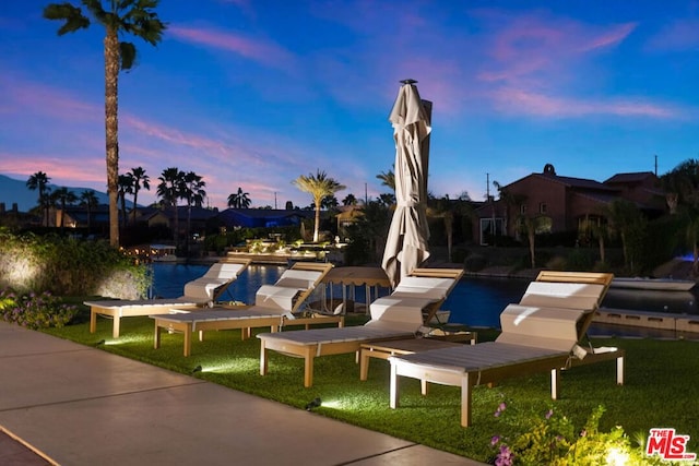 patio terrace at dusk with a lawn and a water view