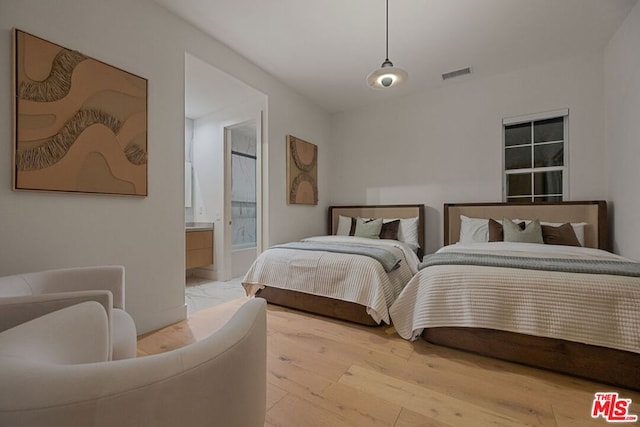 bedroom with connected bathroom and hardwood / wood-style floors