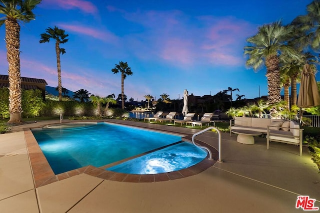 pool at dusk featuring outdoor lounge area and a patio area