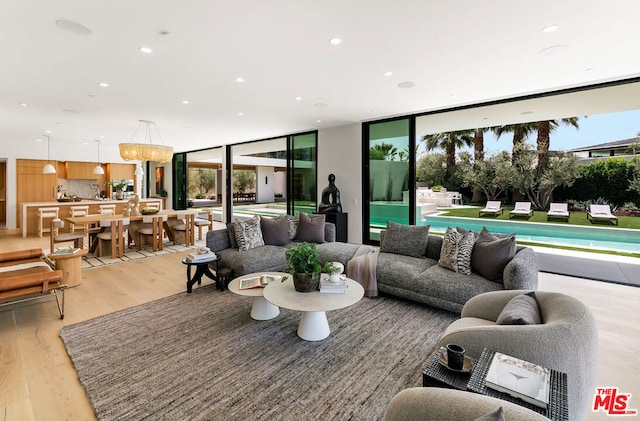 living room featuring light wood-type flooring, an inviting chandelier, and floor to ceiling windows