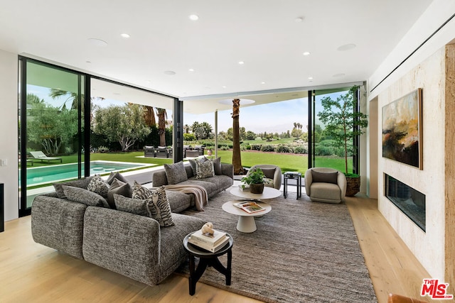 living room featuring a high end fireplace, expansive windows, and light hardwood / wood-style floors