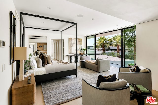 bedroom featuring access to outside, expansive windows, and light hardwood / wood-style floors