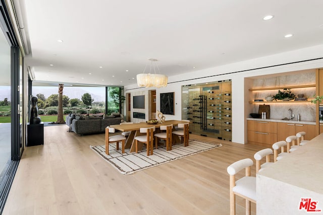 dining space with sink, expansive windows, light hardwood / wood-style floors, and an inviting chandelier