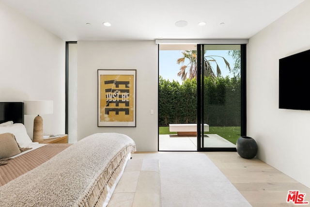 bedroom with expansive windows, light wood-type flooring, and access to outside