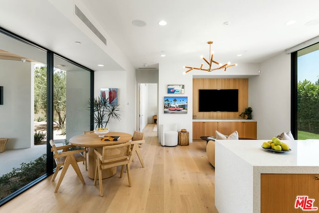 dining room with a wall of windows, light hardwood / wood-style floors, plenty of natural light, and a notable chandelier