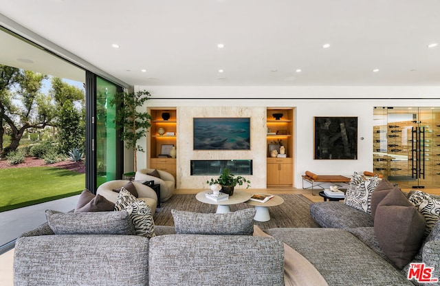 living room with hardwood / wood-style flooring, built in features, and a fireplace