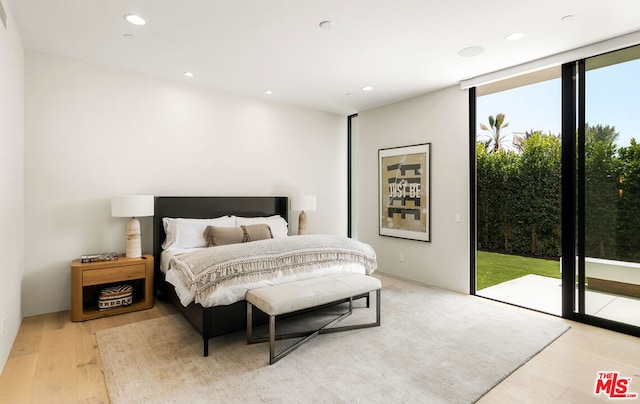 bedroom featuring access to exterior, light wood-type flooring, and a wall of windows