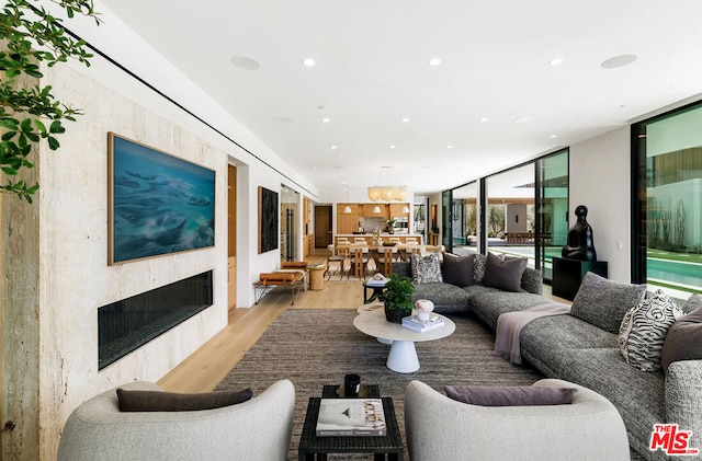 living room with a wall of windows, a high end fireplace, and light wood-type flooring