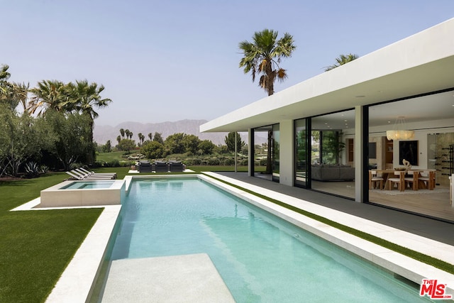 view of pool featuring an in ground hot tub, a mountain view, and a yard