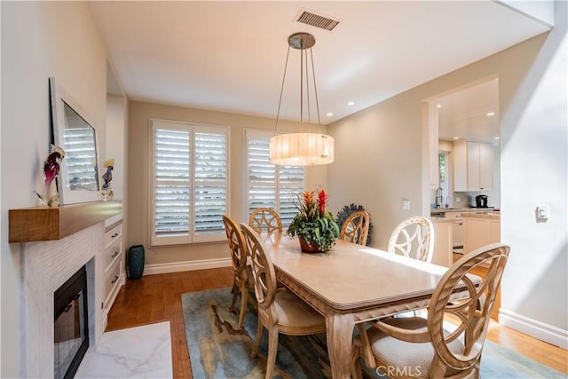 dining space featuring a fireplace, light hardwood / wood-style floors, and sink