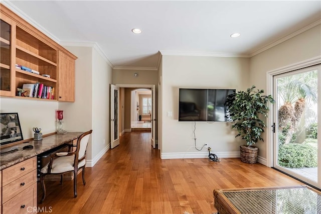 office space featuring built in desk, ornamental molding, and light wood-type flooring