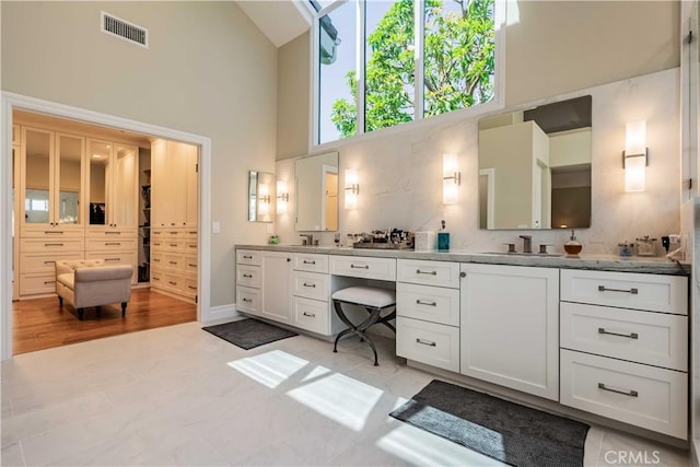 bathroom featuring vanity, tasteful backsplash, and high vaulted ceiling