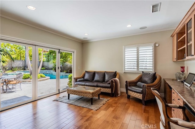 living room featuring french doors, ornamental molding, and light wood-type flooring