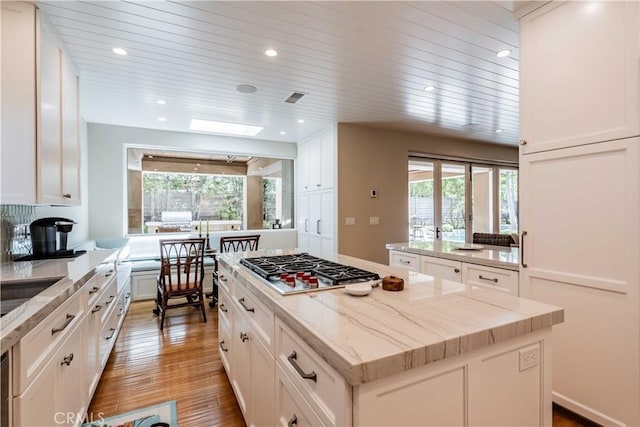 kitchen featuring hardwood / wood-style flooring, a kitchen island, a wealth of natural light, and white cabinetry